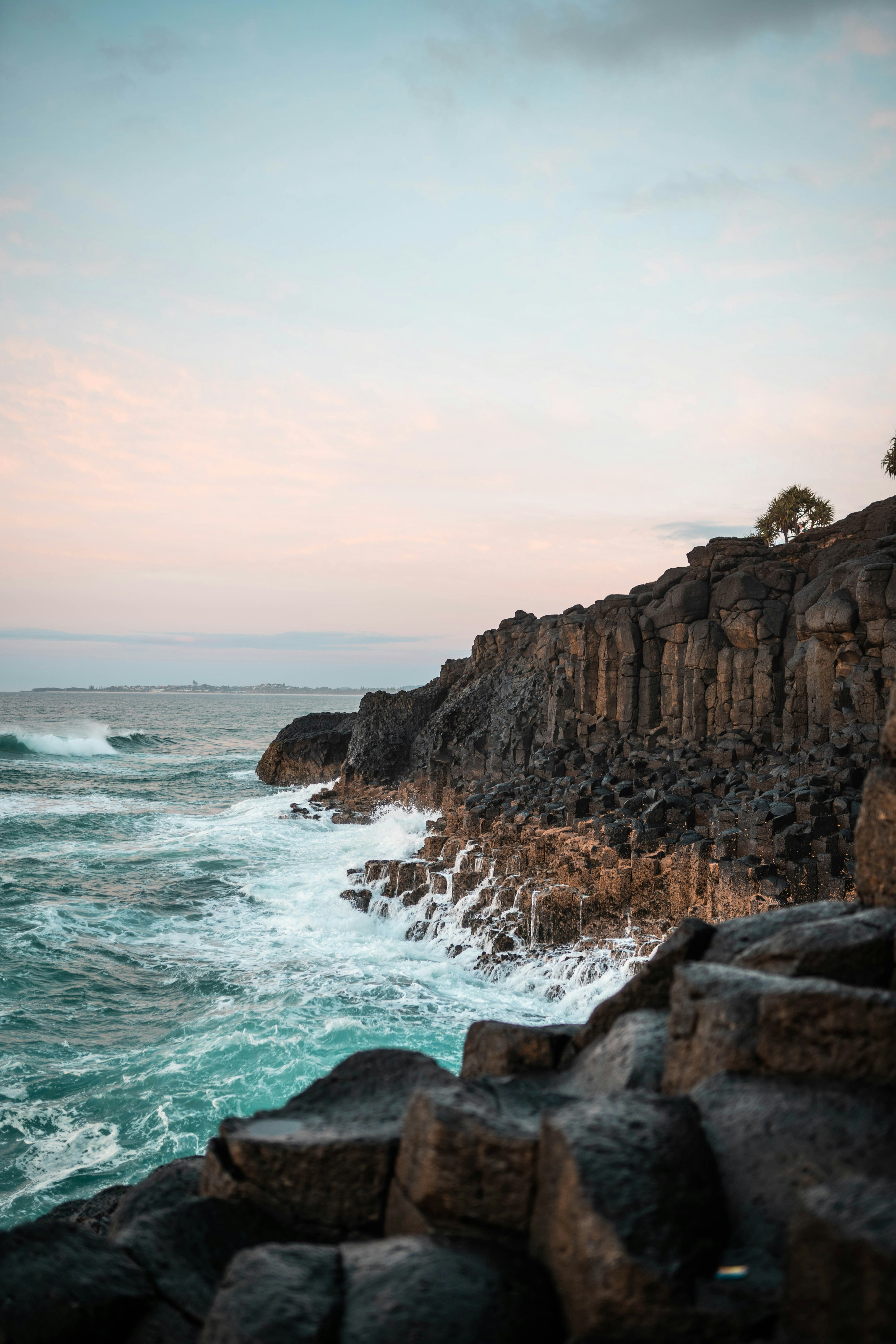 brown rocky mountain beside sea during daytime